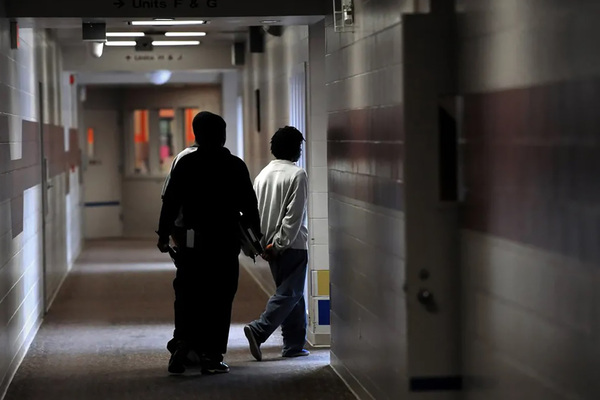 Students with their backs to the camera are escorted through a corridor and into a room at the Marion County Juvenile Detention Center in Indianapolis.