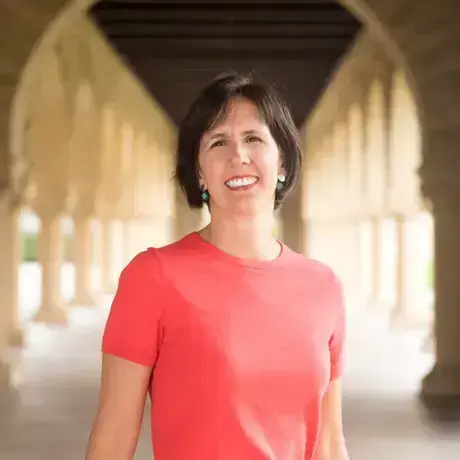Woman in coral shirt smiles, standing in front of arcade.